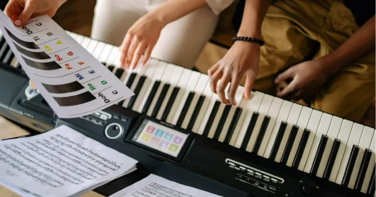 Imagem de duas pessoas estudando harmonia musical no teclado ou algum outro assunto de música