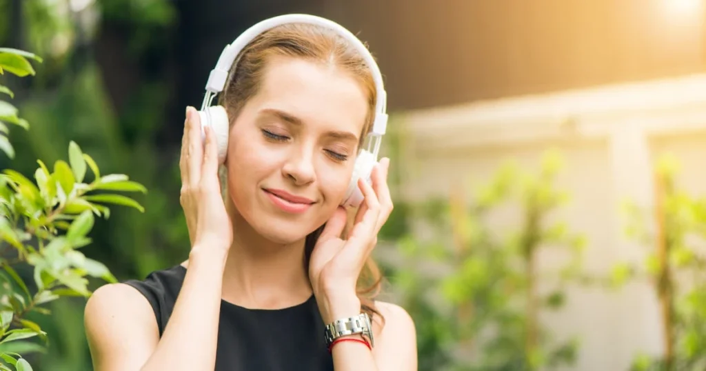 Imagem de uma mulher ouvindo música com um fone de ouvido tipo headset ilustrando a importância da música na vida das pessoas