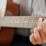Imagem de uma pessoa fazendo um acorde musical no violão. Essa imagem representa o artigo sobre acordes musicais.