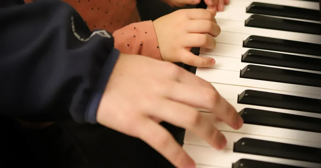 homem e criança com as mãos em um piano