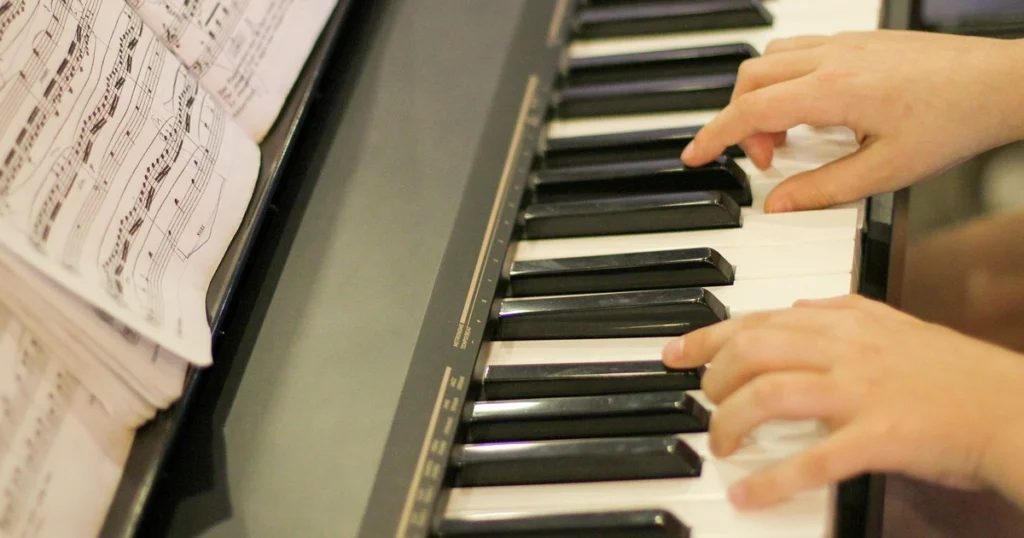 pessoa tocando piano com uma partitura de música na sua frente - imagem usada para representar elementos da harmonia musical